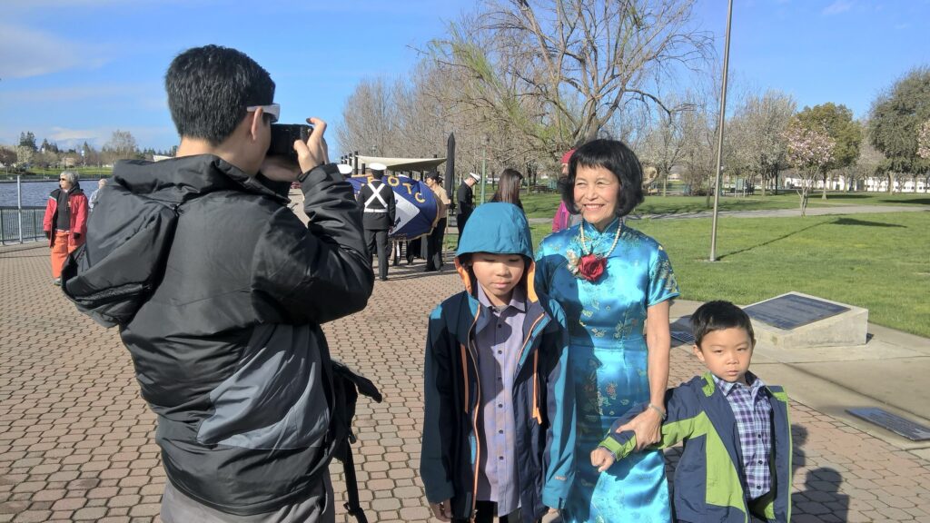Sylvia Wong's son takes a photo of her standing with her two grandsons outside on a tiled walkway by the Stockton riverfront.