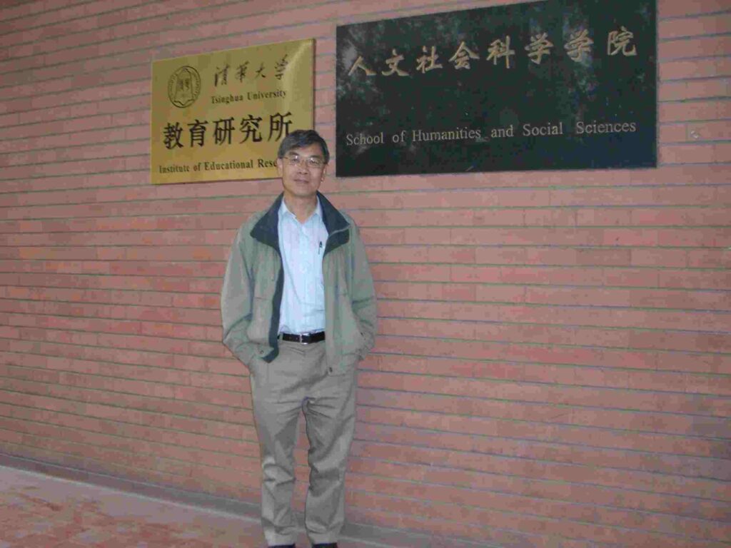 Henry's friend Dr. Lam standing standing in front of a sign identifying the Institute of Educational Research at the Henry Y.T. Wong Building