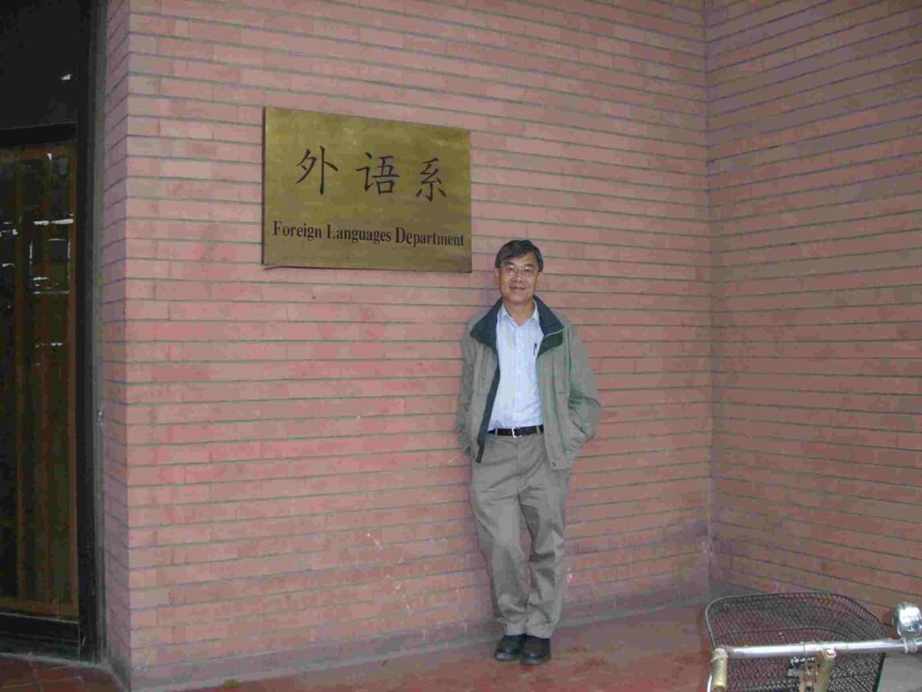 Henry's friend Dr. Lam standing next to a sign identifying the Foreign Languages Department of the Henry Y.T. Wong Building